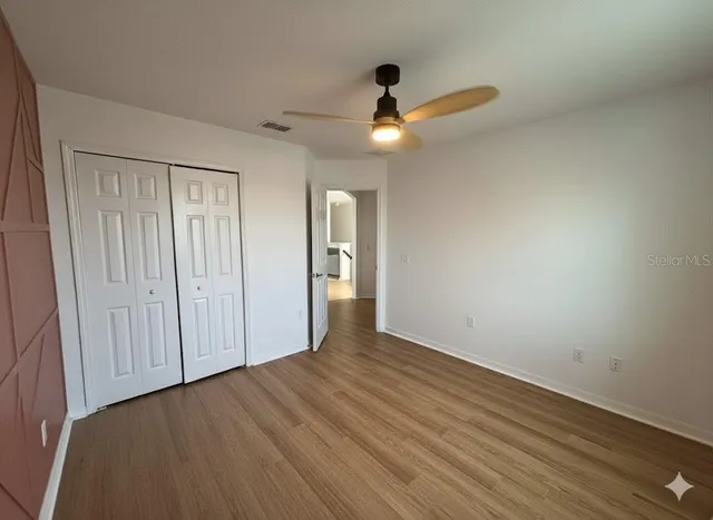 an empty room with wooden floor cabinet and ceiling fan