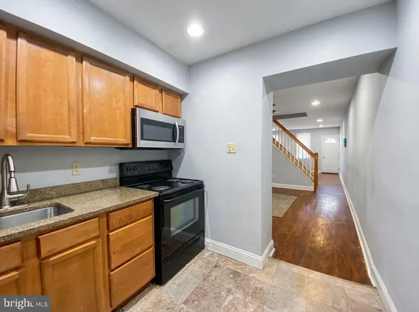 a kitchen with granite countertop wooden cabinets and a stove top oven