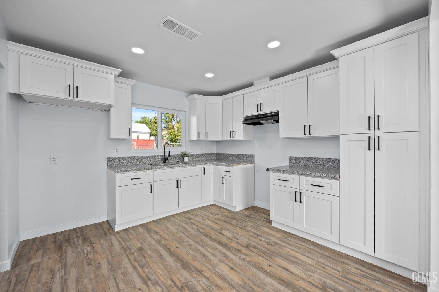 Undisclosed Address Bakersfield, CA 93306 - Photo 12 of 29 a kitchen with granite countertop white cabinets white appliances a sink and a window