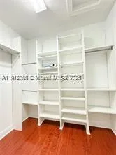a view of an empty room with wooden floor and cabinets