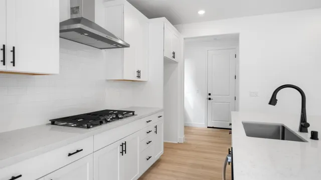 a kitchen with stainless steel appliances a sink a stove and cabinets with wooden floor