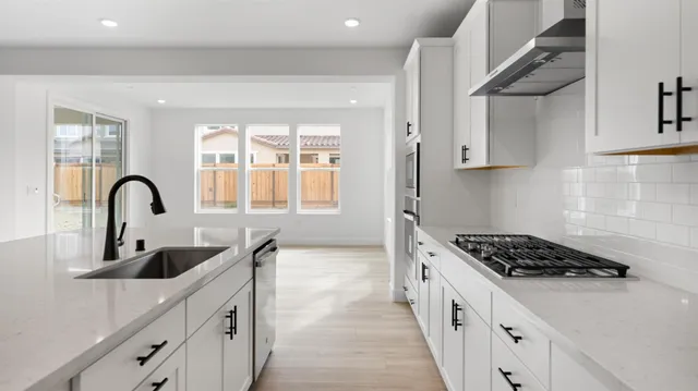 a kitchen with stainless steel appliances a sink a stove and cabinets