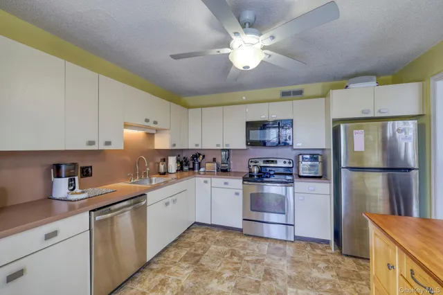 a kitchen with stainless steel appliances granite countertop a refrigerator a sink dishwasher a stove top oven a kitchen island and cabinetry