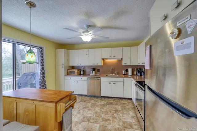 a kitchen with stainless steel appliances granite countertop a sink a stove a refrigerator cabinets and chairs