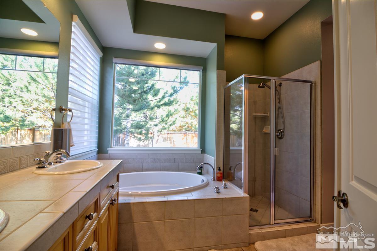 5001 Fall Colors Court Reno, NV 89519 - Photo 23 of 36 a bathroom with a granite countertop sink mirror bathtub and shower