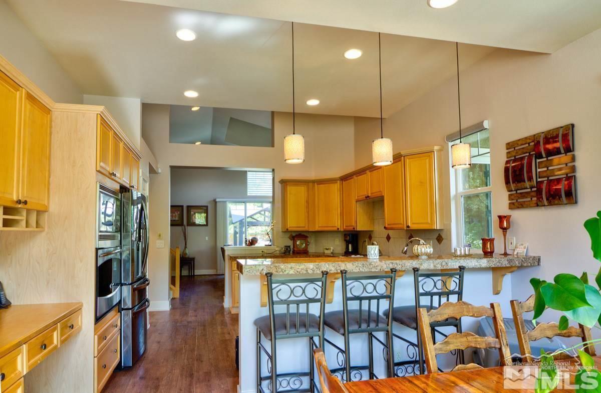 5001 Fall Colors Court Reno, NV 89519 - Photo 9 of 36 a kitchen with stainless steel appliances kitchen island granite countertop a refrigerator a stove a oven a dining table and chairs with wooden floor