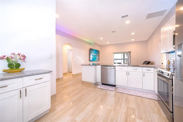 a living room with stainless steel appliances kitchen island granite countertop a couch and a view of kitchen