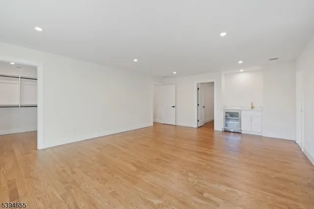 a view of an empty room with wooden floor and windows