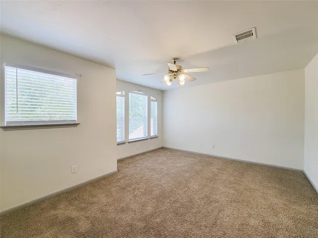 an empty room with windows and chandelier fan