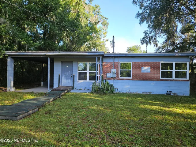 a view of a yard in front of a house with large tree