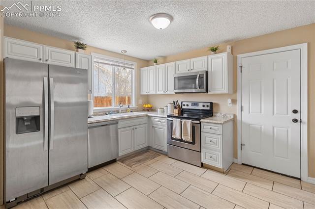 4419 Fenton Road Colorado Springs, CO 80916 - Photo 6 of 21 Kitchen featuring white cabinets, sink, and stainless steel appliances.