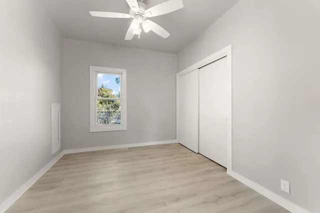 an empty room with wooden floor fan and windows