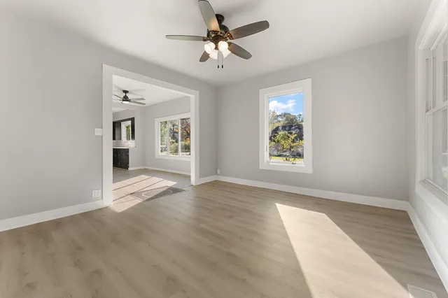 an empty room with windows and ceiling fan