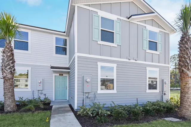 a front view of a house with brick walls and plants
