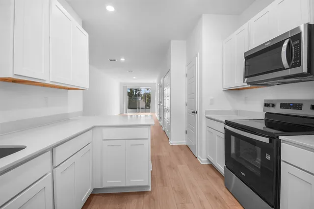 a kitchen with white cabinets stainless steel appliances and wooden floor