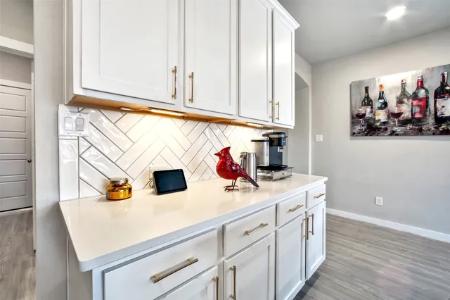 a kitchen with a sink dishwasher and white cabinets with wooden floor