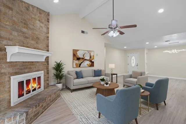 a living room with furniture a fireplace and a ceiling fan