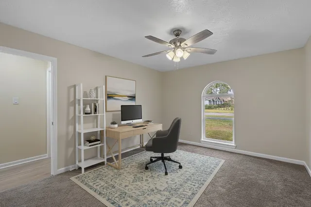 a work room with furniture a rug and a window
