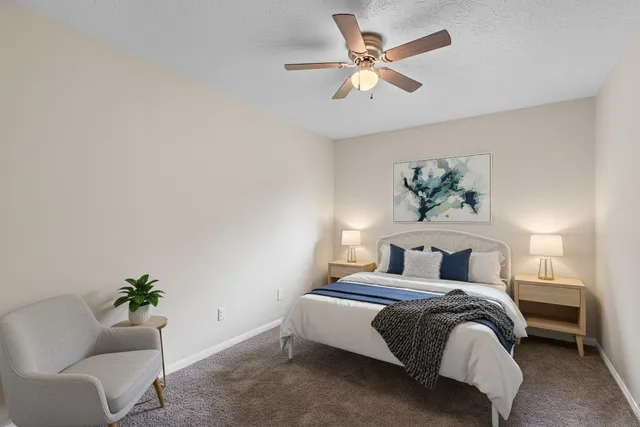 a bedroom with a bed painting on wall and a potted plant