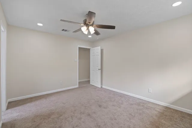 an empty room with a chandelier fan and windows