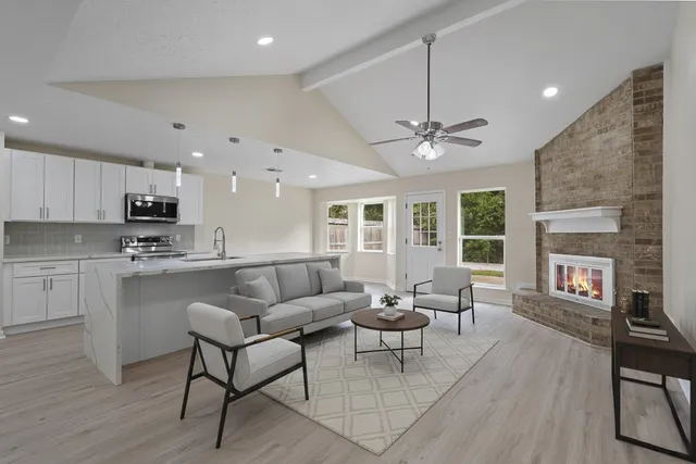 a living room with stainless steel appliances furniture and a kitchen view