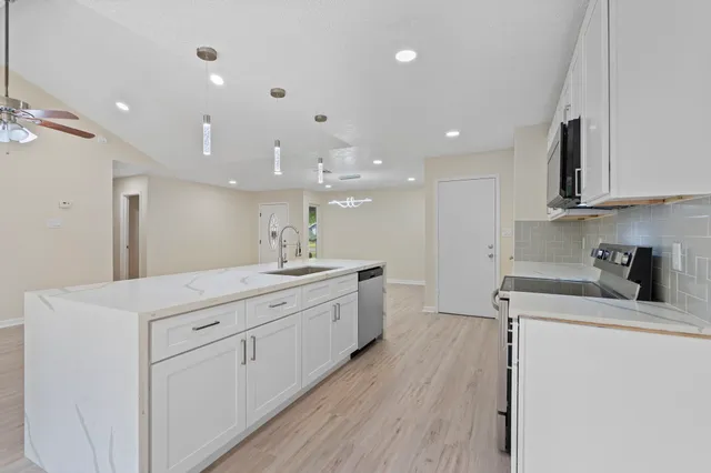 a view of a kitchen with kitchen island a sink stainless steel appliances and cabinets