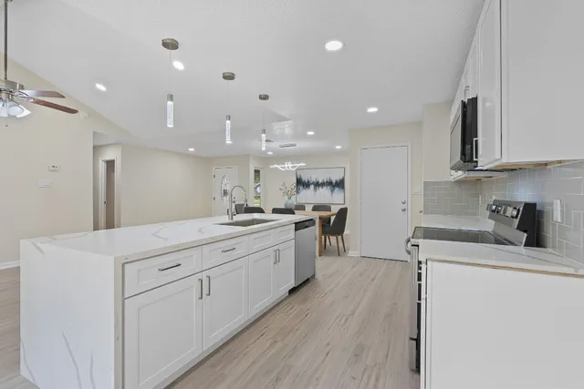 a kitchen with white cabinets appliances and sink