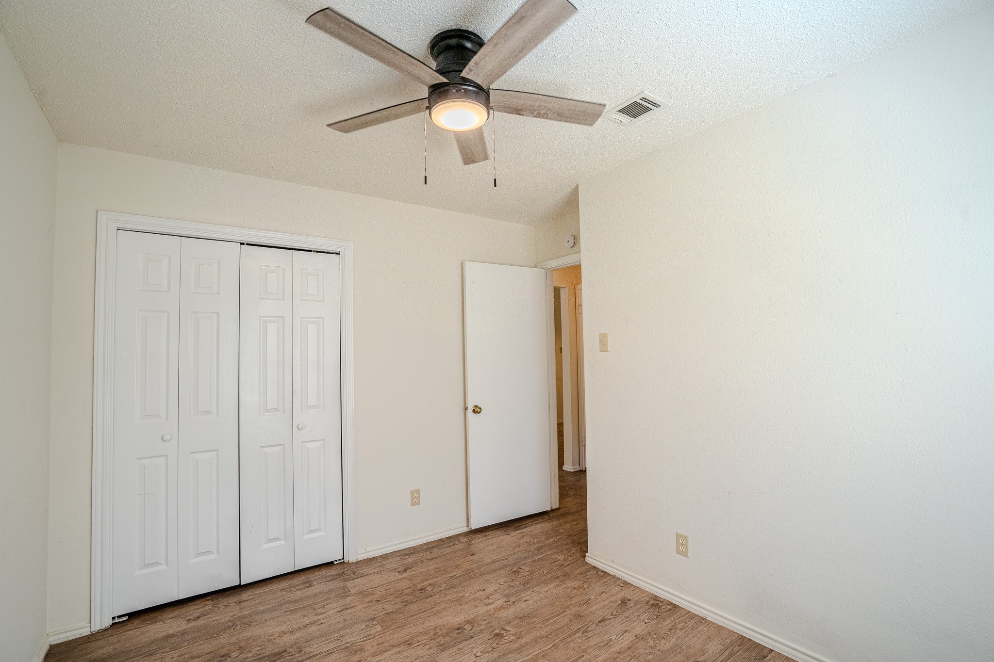 517 Cutty Trail, Unit B Lakeway, TX 78734 - Photo 7 of 16 A well-maintained bedroom offers wood-look flooring and a modern ceiling fan for comfort.