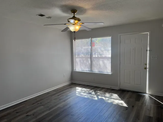a view of empty room with wooden floor and fan
