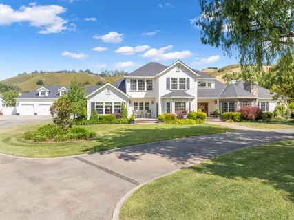a view of house with a big yard and large trees