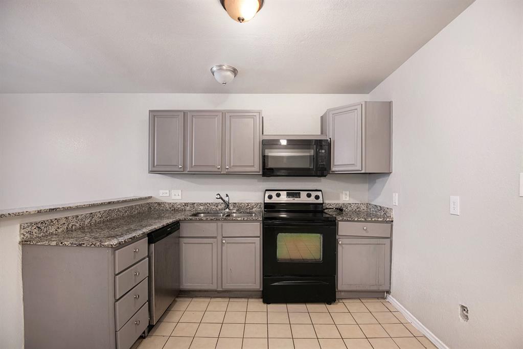 4936 Flamingo Road Fort Worth, TX 76119 - Photo 11 of 24 a kitchen with a stove a sink and a microwave