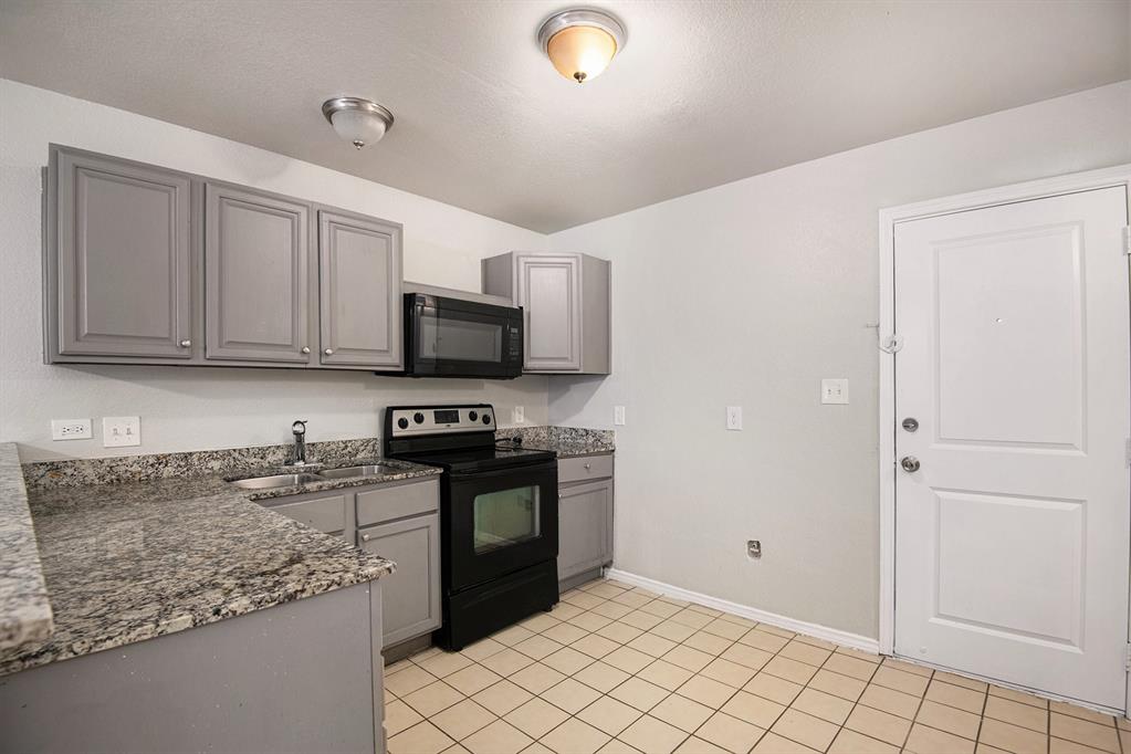 4936 Flamingo Road Fort Worth, TX 76119 - Photo 10 of 24 a kitchen with stainless steel appliances granite countertop a sink stove and microwave