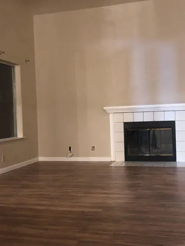 a view of empty room with wooden floor and a fireplace