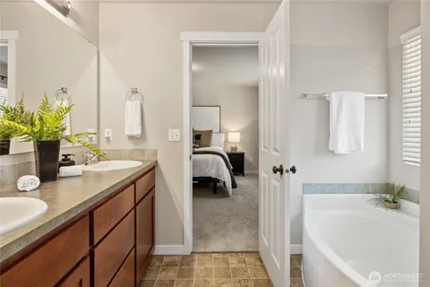 a en suite bathroom with a granite countertop sink and a bathtub