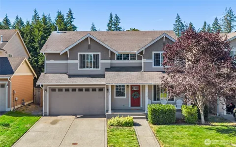 a view of a house with a yard plants and large tree