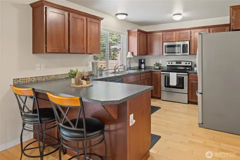 a kitchen with stainless steel appliances granite countertop a table chairs microwave and sink