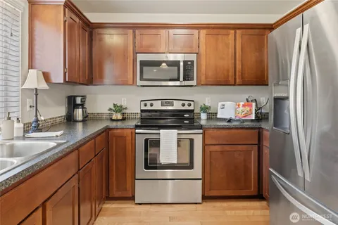 a kitchen with stainless steel appliances granite countertop a refrigerator sink and stove