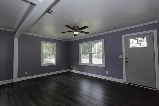 an empty room with wooden floor and windows