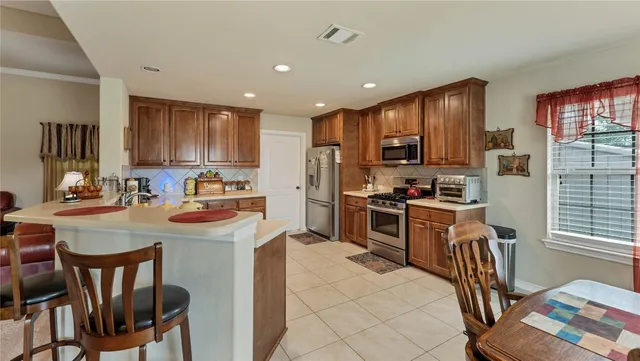 a kitchen with kitchen island granite countertop wooden cabinets a stove a sink a oven a dining table and chairs