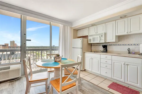 a kitchen with stainless steel appliances kitchen island granite countertop a refrigerator a stove a dining table and chairs with wooden floor