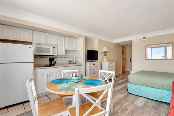 a kitchen with stainless steel appliances granite countertop a sink a stove a refrigerator and white cabinets with wooden floor