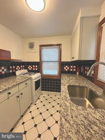 a kitchen with granite countertop a sink a stove and a cabinets