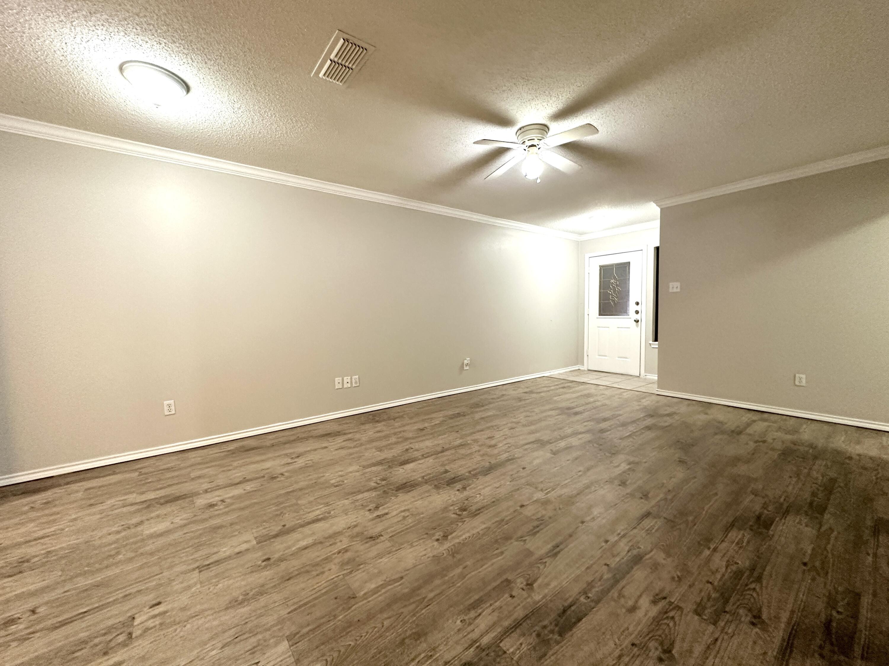 615 North Elkhart Avenue Lubbock, TX 79416 - Photo 3 of 15 an empty room with a ceiling fan and wooden floor