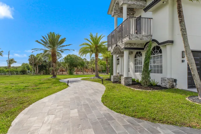 a view of a house with a big yard plants and palm trees