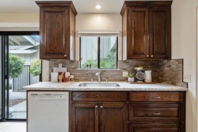 a kitchen with granite countertop a sink window and cabinets