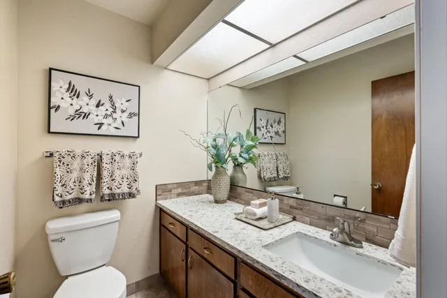 a bathroom with a granite countertop toilet sink and mirror