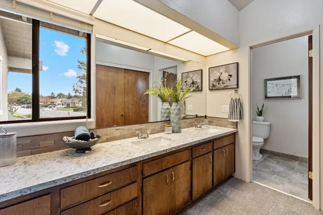 a bathroom with a granite countertop sink mirror and toilet