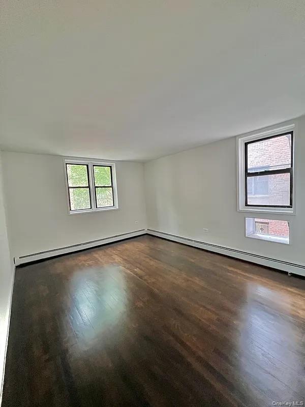 55-30 99th Street, Unit 3F Queens, NY 11368 - Photo 5 of 8 a view of an empty room with wooden floor and a window
