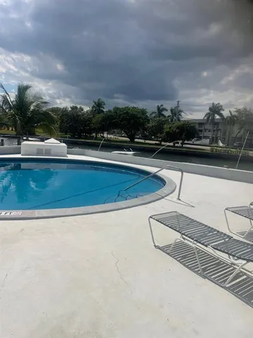 a view of swimming pool with lawn chairs and iron fence