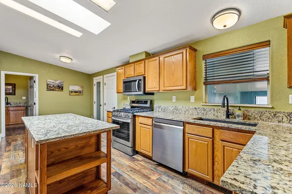 a kitchen with stainless steel appliances granite countertop wooden cabinets a stove a sink and dishwasher next to a window